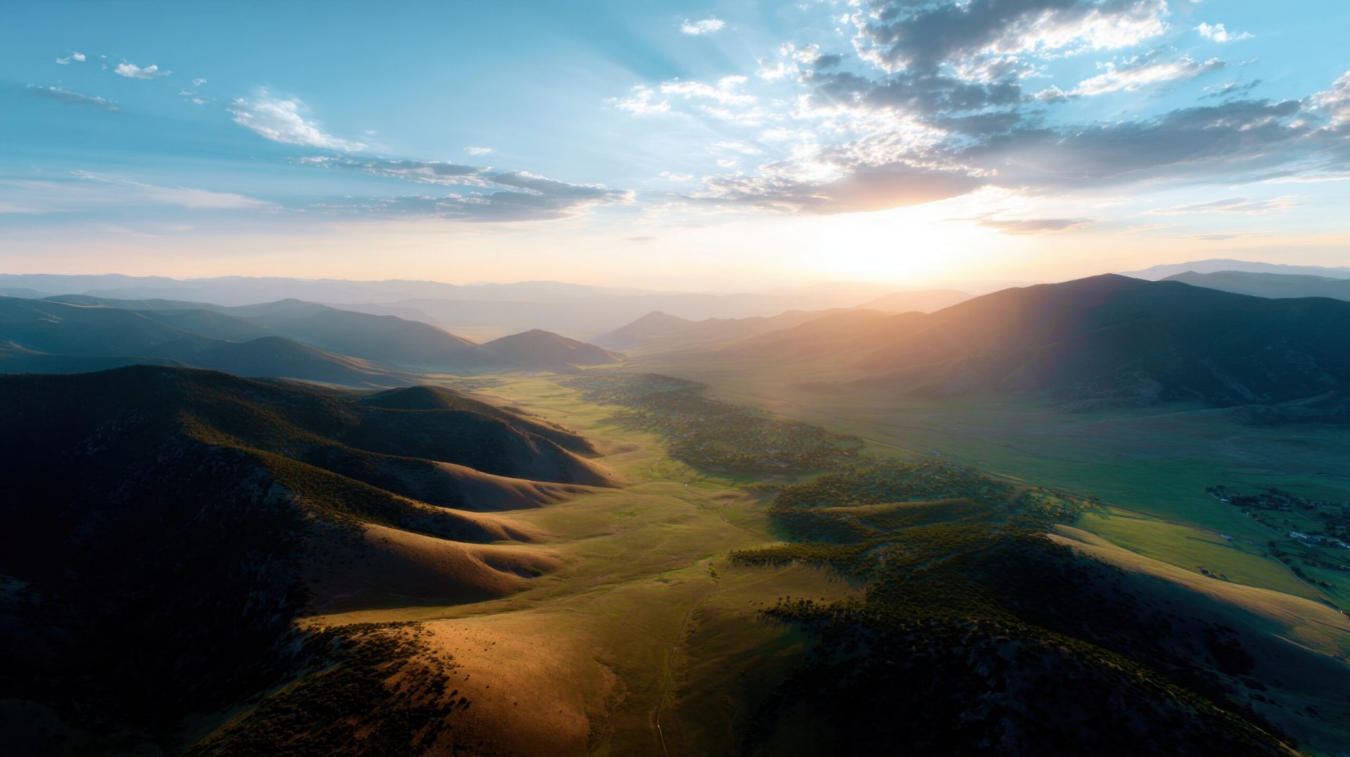 High-altitude aerial of mountain valley at sunset, golden light washing over rolling hills, tranquil and inspiring landscape for meditation or lifestyle stock photo