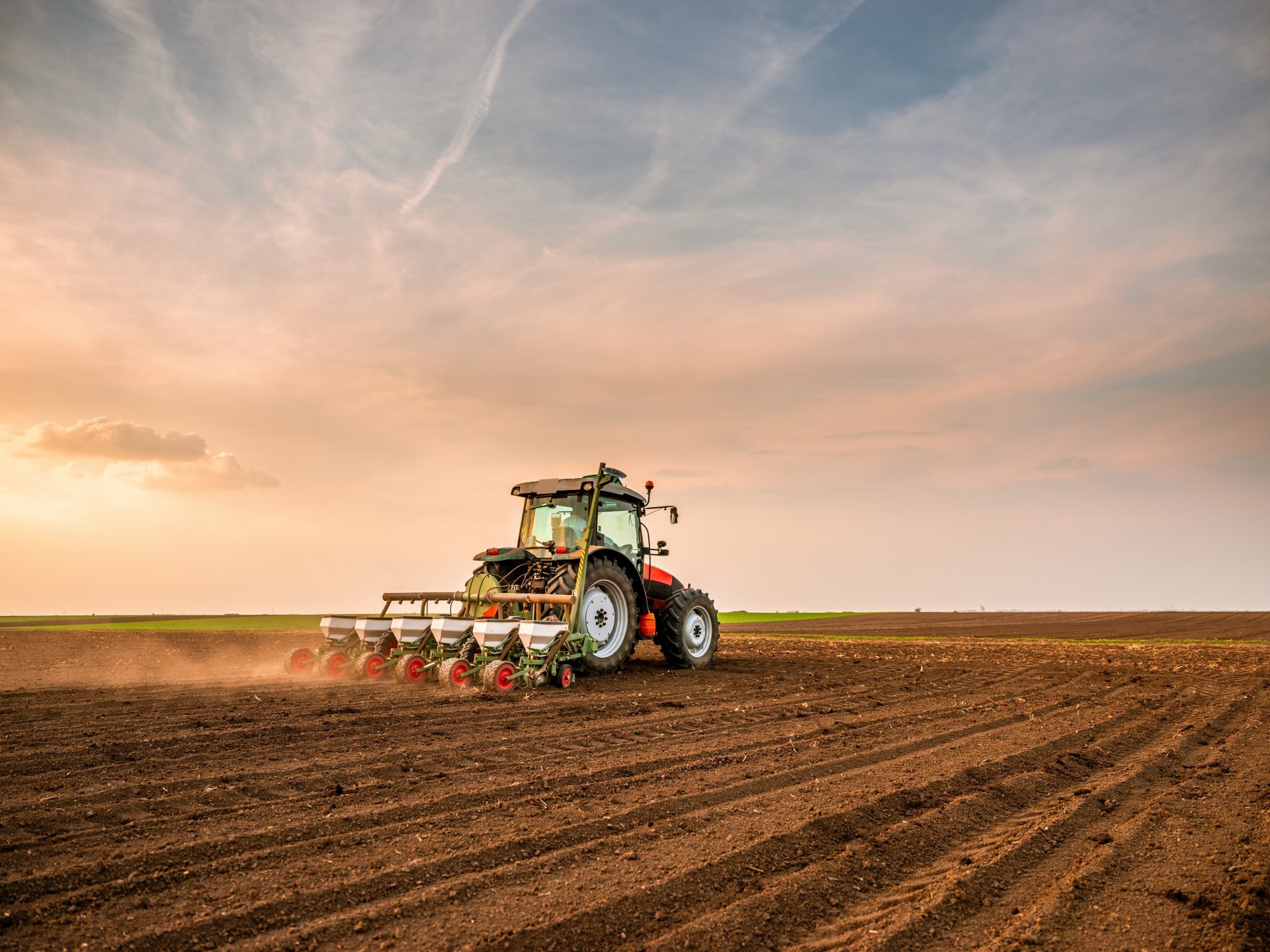 Tractor drilling seeding crops at farm field. Agricultural activ